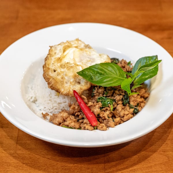 Sticky Rice Bites' Thai basil chicken with a fried egg, rice, and a red chili.