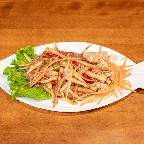 Sticky Rice Bites' papaya salad with peanuts, pork rinds, and carrots on a fish-shaped plate.
